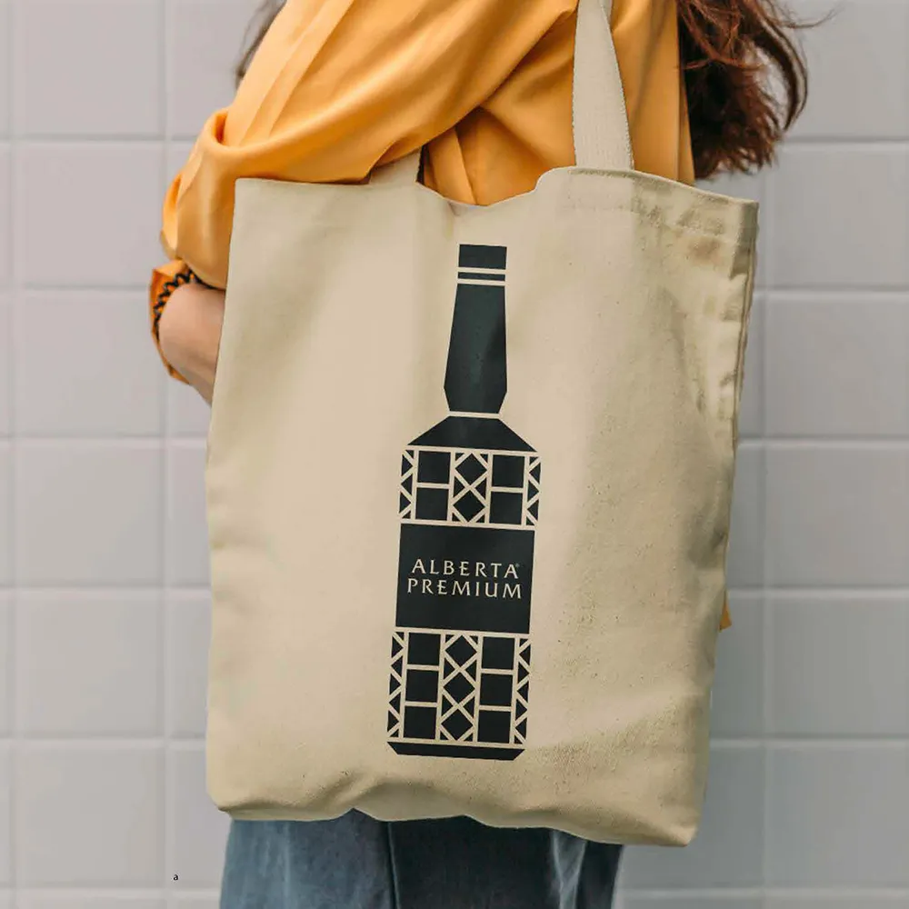 Person holding canvas bag with Alberta Premium bottle graphic Alberta