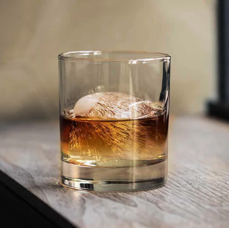 Whisky glass with ice on wooden table in natural light Alberta